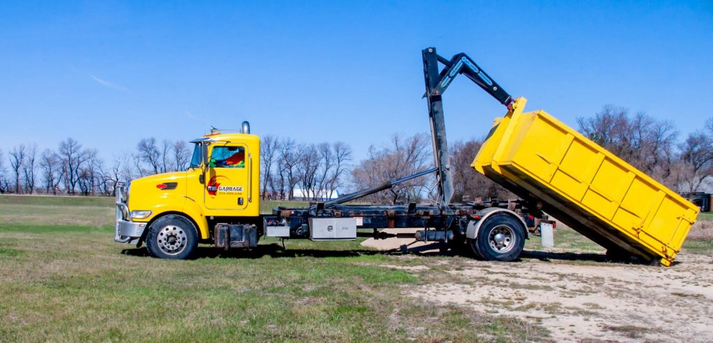 Mr Garbage truck delivering yellow dumpster – garbage bin rental Winnipeg for junk hauling, trash removal, and debris cleanup services.