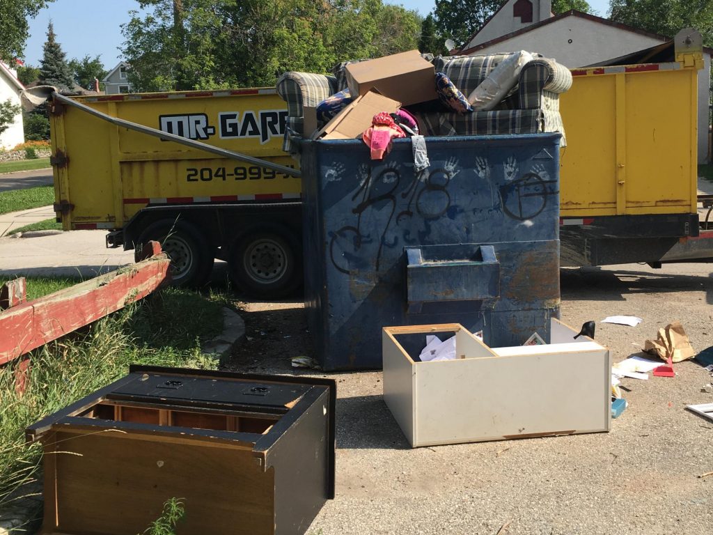 Mr. Garbage junk removal bin in Winnipeg filled with old furniture, household waste, and debris during a residential cleanout.