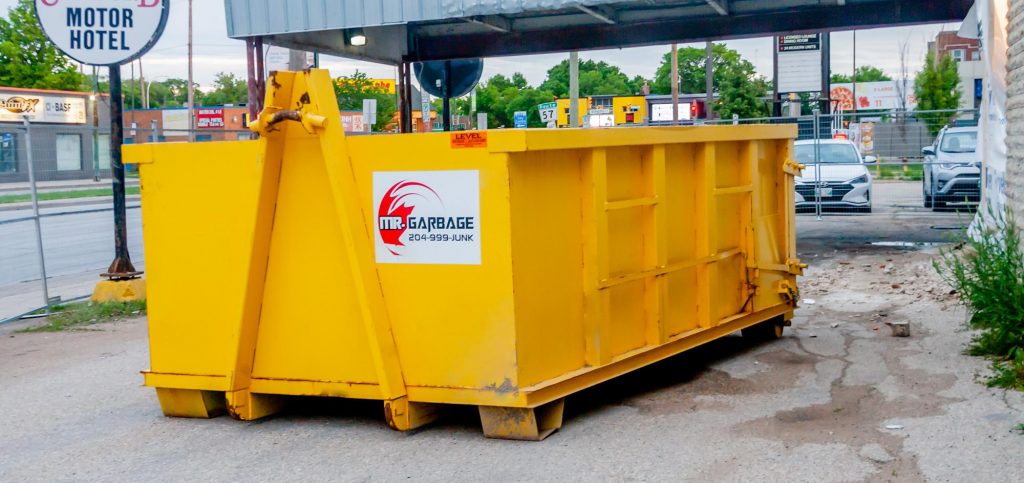Mr. Garbage yellow dumpster rental placed outside a Winnipeg property for junk removal and waste management.