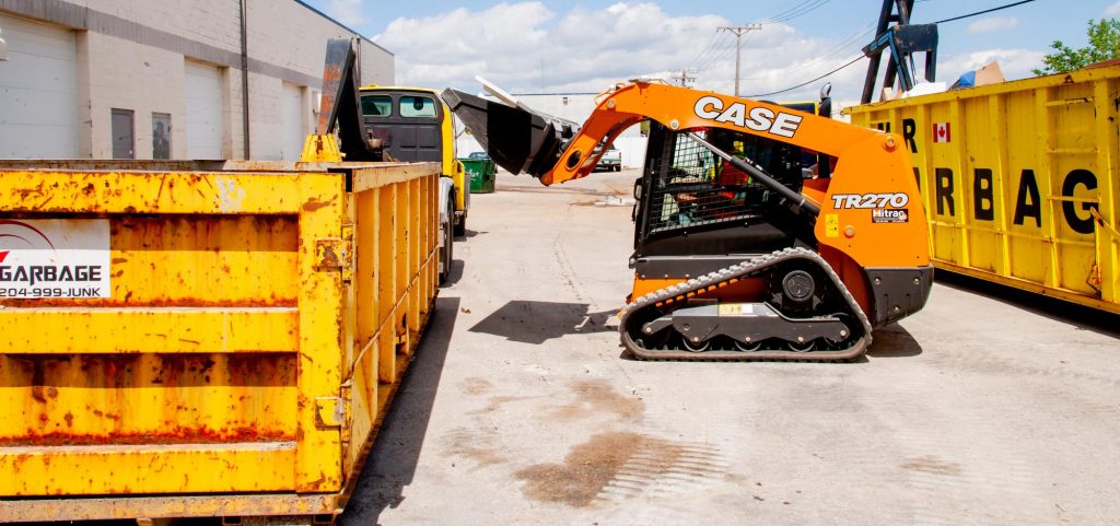 Construction cleanup with skid steer loader dumping debris into a Mr. Garbage dumpster rental in Winnipeg.