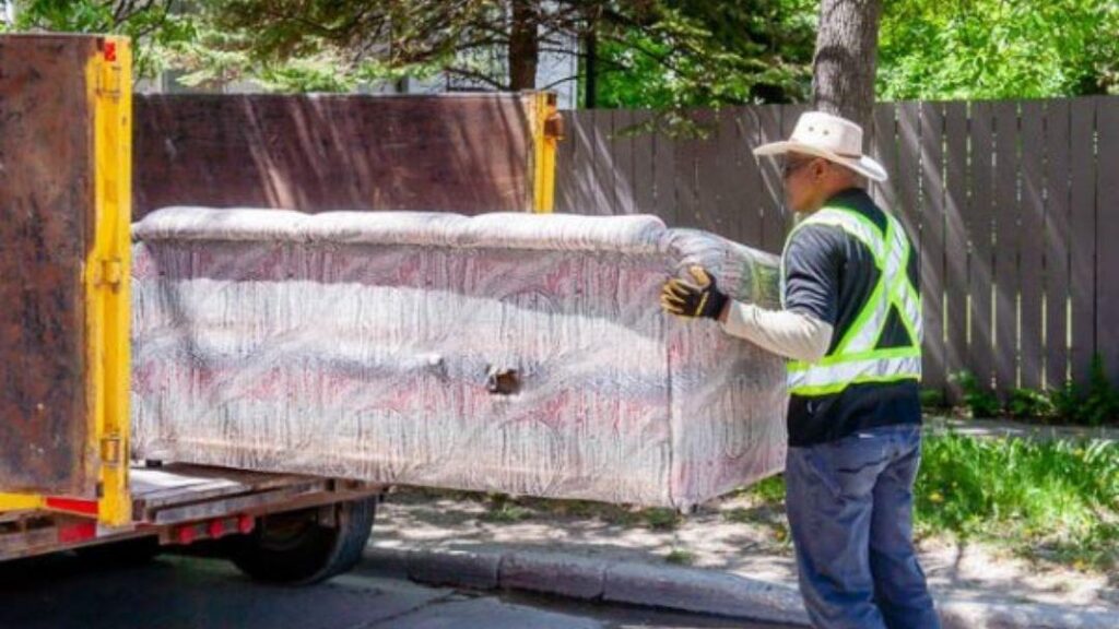 Mr Garbage worker loading old couch onto truck – junk removal service and furniture removal near me in Winnipeg.