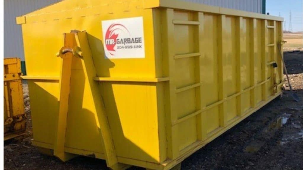 Mr. Garbage yellow dumpster rental outside a commercial building for waste disposal and junk removal in Winnipeg.